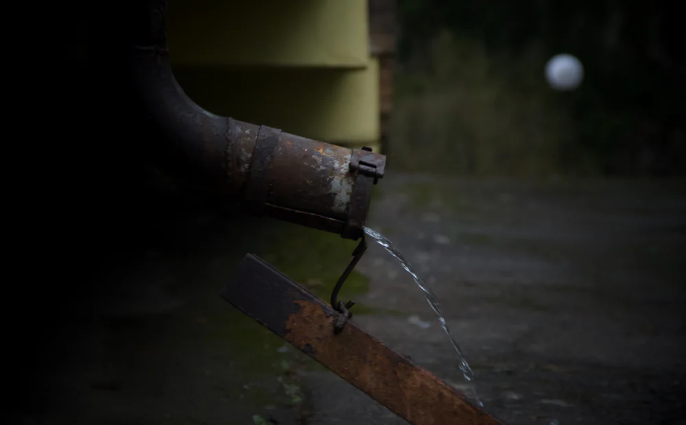 Bajante vertiendo agua de lluvia junto a una fachada